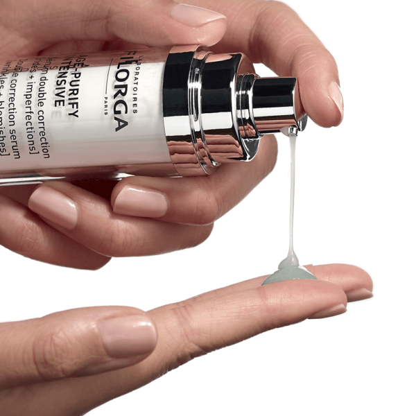 Hand holding a skincare serum bottle with dropper, showing product on finger