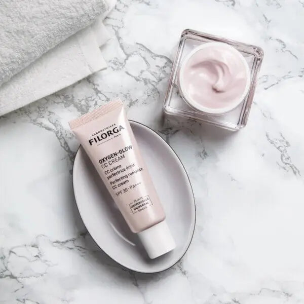 Filorga Oxygen Glow CC Cream tube and jar on a marble surface