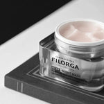 Filorga night mask jar on a black surface with a white background