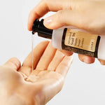 A close-up of a hand dispensing clear gel from a COSRX Advanced Snail 96 Mincer Essence bottle into another hand, on a clean white background.